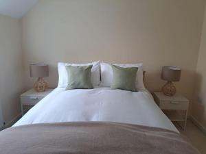 1 cama blanca grande con 2 lámparas en 2 mesas en Vibrant Coastal Village Retreat- private parking en Lympstone