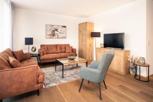 a living room with a couch and a television at Bellevue Residences - Luxurious Lakeside Apartments in Zell am See