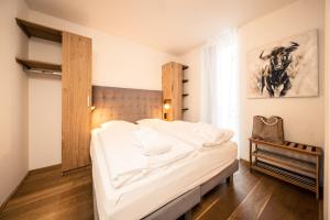 a bedroom with a bed with white sheets and a window at Bellevue Residences - Luxurious Lakeside Apartments in Zell am See
