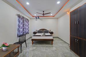 a room with a bed and a table and a chair at Capital O Hotel Lakshmi Residency in Tirupati