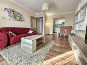 Dj apartment Kostrena في Šodići: غرفة معيشة مع أريكة حمراء وطاولة