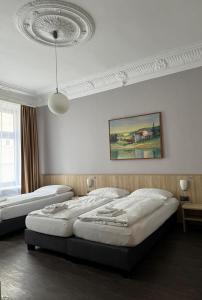 a bedroom with two beds and a painting on the wall at Hotel Kieler Hof am Hauptbahnhof - Hamburg Central Station in Hamburg