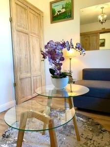 a glass table with a vase of purple flowers on it at CHATA OTWARTYCH OKIENNIC Pokoje Gościnne in Supraśl