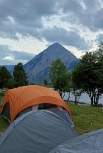 a tent in a field with a mountain in the background at GUREZ CAMPSITE- WILDWOOD in Kanzalwan