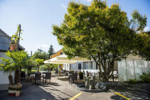 eine Terrasse mit Tischen, Stühlen und einem Baum in der Unterkunft Hotel Sternen in Räterschen