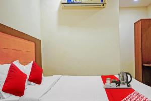 a bedroom with a bed with red pillows at Hotel Swapna in Vijayawāda