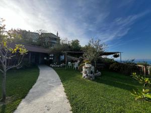 a house with a grass yard with a pathway at Hotel Restorant Olti in Draç