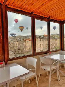 a room with two tables and windows with hot air balloons at Yellow Stone House in Goreme
