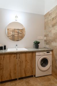 a bathroom with a sink and a washing machine at Várvédőház Apartmanok Eger in Eger +15 photos