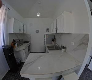 eine kleine Küche mit weißen Schränken und einem Waschbecken in der Unterkunft Hotel El Legendario in Sosúa