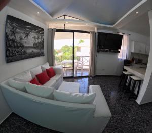 ein Wohnzimmer mit einem weißen Sofa und roten Kissen in der Unterkunft Hotel El Legendario in Sosúa