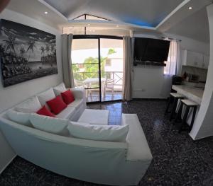 ein Wohnzimmer mit einem weißen Sofa und roten Kissen in der Unterkunft Hotel El Legendario in Sosúa