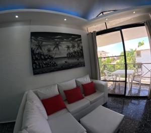 een woonkamer met een witte bank en rode kussens bij Hotel El Legendario in Sosúa