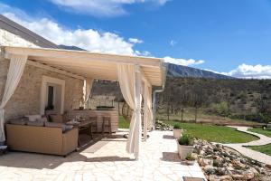 une pergola avec un canapé et une table sur une terrasse dans l'établissement Stone House With Jacuzzi "DINARA", à Kijevo