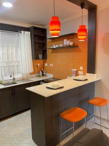 a kitchen with an island with two orange chairs at Athena Apartments in Kampala