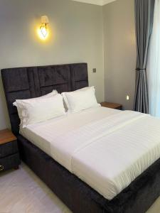 a bedroom with a large bed with white sheets and pillows at Athena Apartments in Kampala