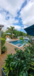 a large swimming pool with a wooden deck at Le Palmier de la Paix in Le Tampon