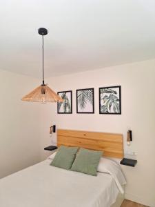 a bedroom with a white bed with four pictures on the wall at Apartamento Premium PLAZA MAYOR con PARKING in Ávila