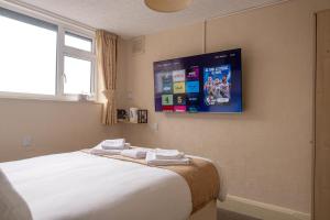 Schlafzimmer mit einem Bett und einem TV an der Wand in der Unterkunft The Kildare in Skegness