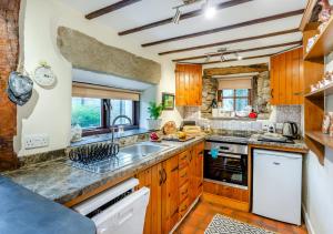 cocina grande con armarios de madera y fregadero en Newby Cottage en Newby