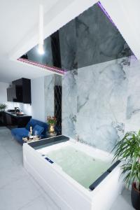 a bath tub in a room with a marble wall at Apartament Jacuzzi in Gdynia