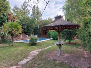 un paraguas sentado en el césped junto a una piscina en Casa guerrero, con piscina en chacras, en Ciudad Lujan de Cuyo