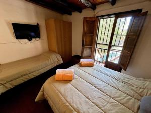 Dos camas en una habitación con televisión y ventana. en Casa guerrero, con piscina en chacras, en Ciudad Lujan de Cuyo