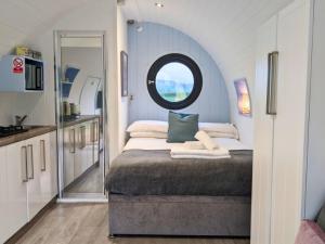 a small bedroom with a bed and a round window at The Kingfishers Burrow in Llandovery