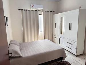 a white bedroom with a bed and a dresser at Casa bem localizado em Sinop in Sinop