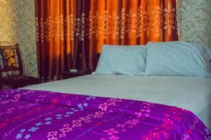 Una cama con una manta morada encima. en RICO HOTEL GH, en Nkawkaw
