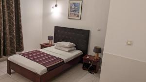 1 dormitorio pequeño con 1 cama y 2 mesitas de noche en HOTEL ALIA en Yibuti