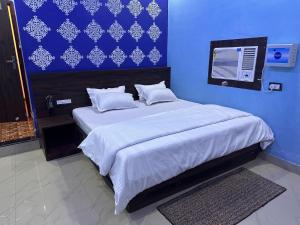 a blue bedroom with a large bed with white sheets and pillows at OYO The Mount View in Jamshedpur