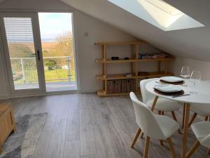 a dining room with a table and chairs and a window at Y Llofft, Llanrhidian, Gower in Swansea