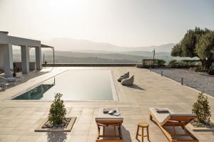 a swimming pool with two tables and chairs next to a house at Luxurious 6- Bed Private Villa in Heraklion Crete in Athánatoi