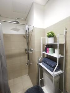 ein Bad mit einer Dusche, einem Waschbecken und Regalen in der Unterkunft Cozy 1BR in Shore Residences MOA by Staycation Deals by L in Manila
