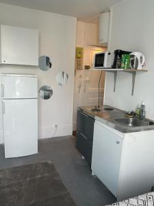 een keuken met witte kasten en een witte koelkast bij Studio cosy - Paris 16 in Parijs
