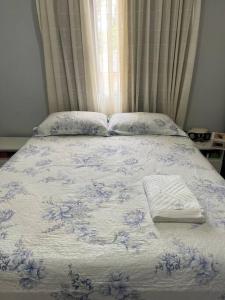 a bed with a blue and white blanket and pillows at 2 Quartos Aconchegante - Cohama in São Luís