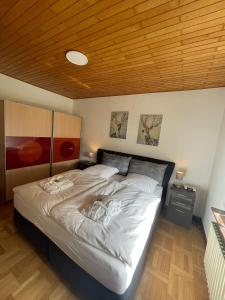 a large bed in a bedroom with a wooden ceiling at Schöne helle Ferienwohnung 35606 Solms Lahn Küche separat in Braunfels