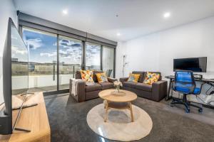a living room with a couch and a chair and a television at Park Ave City delight in Canberra