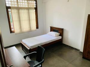 ein kleines Schlafzimmer mit einem Bett und einem Stuhl in der Unterkunft Privet Home Stay in Wattala
