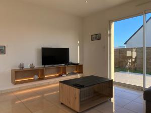 a living room with a flat screen tv and a coffee table at 1100-Maison au cœur du village de Planguenoual. in Planguenoual