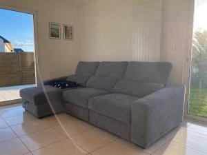 a gray couch in a living room with a large window at 1100-Maison au cœur du village de Planguenoual. in Planguenoual