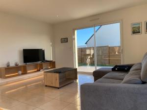 a living room with a couch and a flat screen tv at 1100-Maison au cœur du village de Planguenoual. in Planguenoual