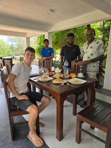 een groep mannen die rond een houten tafel zitten bij Rock Villa Relax City Home in Mihintale