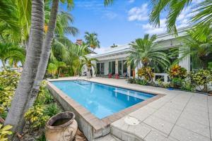 a swimming pool in front of a house with palm trees at Casa del Sol in Fort Lauderdale