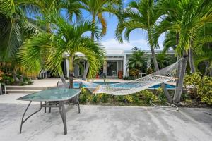 a hammock and a table in front of a house at Casa del Sol - Heated Saltwater Pool - Waterfront - Paddle Boards in Fort Lauderdale