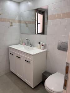 een witte badkamer met een wastafel en een toilet bij Kosher for Passover Beachfront Apartment in Netanya
