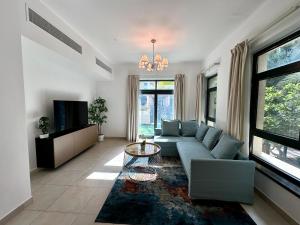 un salon avec un canapé bleu et une télévision dans l'établissement Lux BnB Travo Tower I Private Garden I Lake View, à Dubaï
