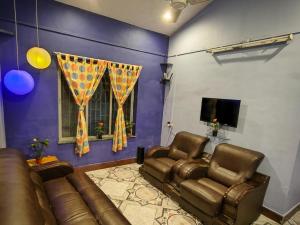 sala de estar con 2 sillas de cuero y TV en Blue Lagoon 2bhk en Lonavala
