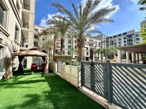 a garden with a fence and palm trees in a building at Lux BnB Travo Tower I Private Garden I Lake View in Dubai